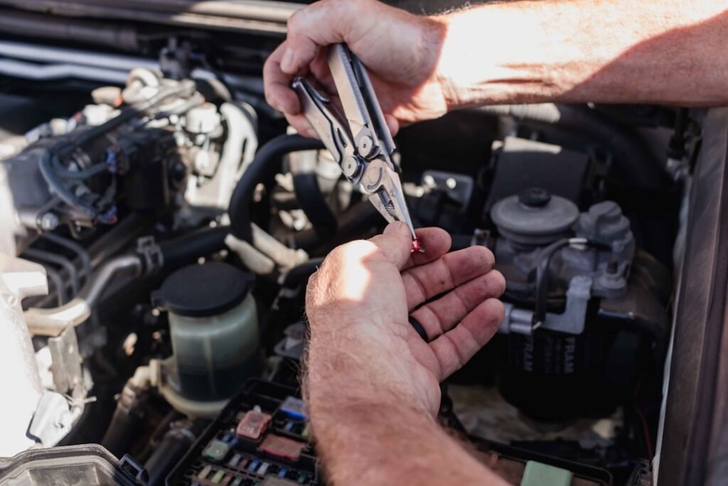 Manos trabajando en el vano motor de un coche durante una revisión de mantenimiento