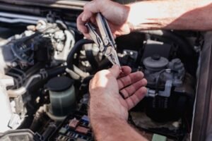 Manos trabajando en el vano motor de un coche durante una revisión de mantenimiento