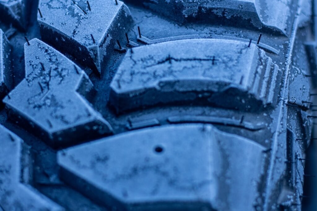 Primo piano del battistrada di un pneumatico invernale con neve tra i tasselli