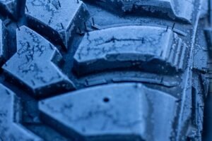 Primo piano del battistrada di un pneumatico invernale con neve tra i tasselli