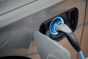 An EV charging connector plugged into a car's charge port — the kWh delivered from the wall are what real miles-per-kWh is measured against