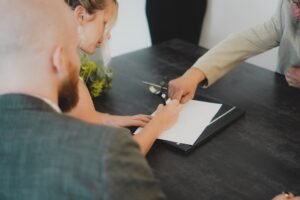 Firma di un atto di vendita su una scrivania: l'autentica della firma è il primo dei due adempimenti del passaggio di proprietà auto