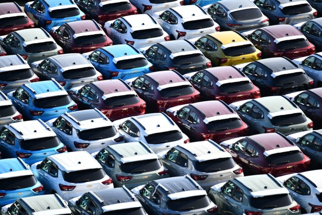 Filas de coches nuevos aparcados en una campa, como los de una flota de renting, vistos desde arriba