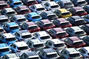 Filas de coches nuevos aparcados en una campa, como los de una flota de renting, vistos desde arriba