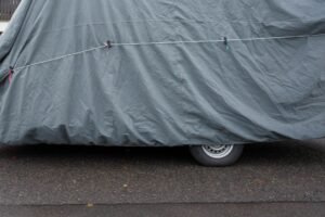 Auto coperta da un telo e legata, ferma a bordo strada: con il fermo amministrativo iscritto al PRA il veicolo resta di proprieta ma non puo circolare