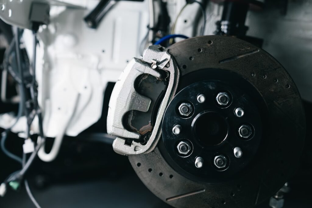 Brake caliper, pad and rotor seen through the wheel — the friction material whose thickness decides how long brake pads last