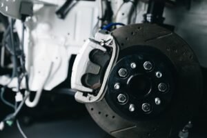 Brake caliper, pad and rotor seen through the wheel — the friction material whose thickness decides how long brake pads last