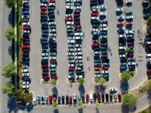 Aerial view of a parking lot full of cars — leasing and buying differ most in what the contract is required to disclose