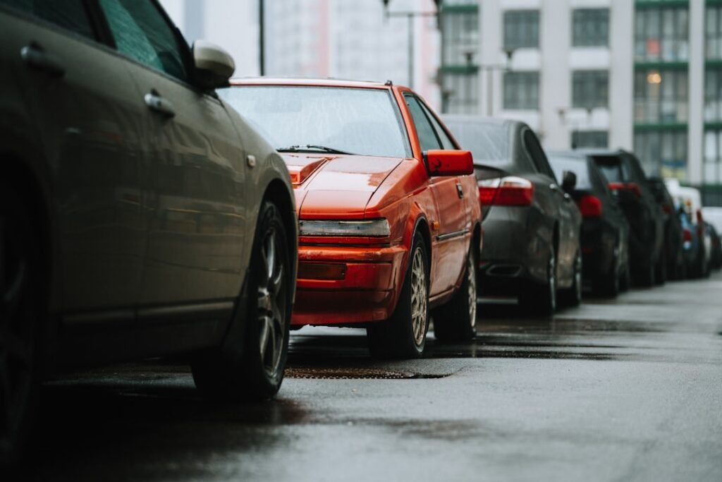 Fila de coches aparcados muy juntos en una calle mojada, el sitio donde ocurren la mayoría de los golpes de chapa