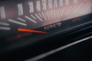 Close-up of a five-digit mechanical car odometer reading 56947 miles — the one number a used-car seller must certify in writing